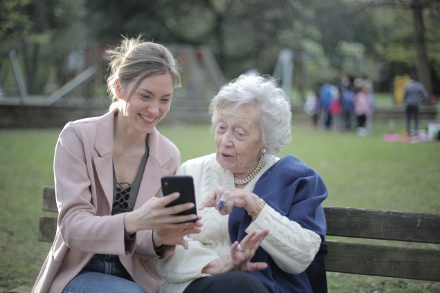 Twee dames kijken in het park op een smartphone