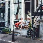Een man en een vrouw zitten in de deuropening van een Nederlands grachtenpand