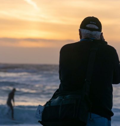 Man maakt foto's van surfers op het strand