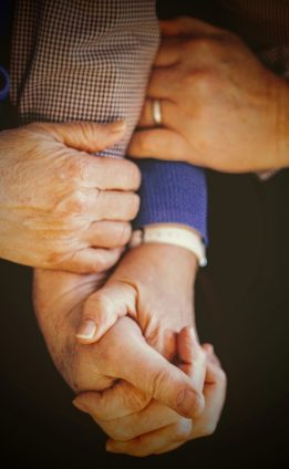 Twee mensen houden elkaars handen vast